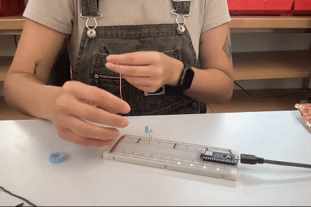 breadboard with arduino powering a blue LED with two jumper wires used as a switch